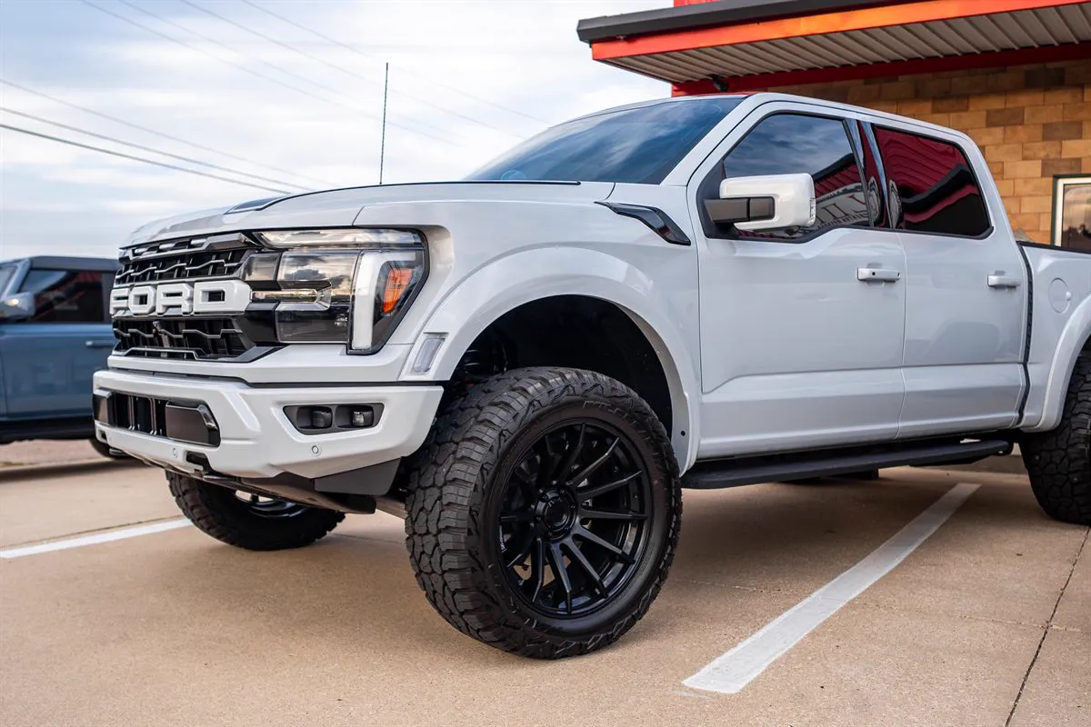 Lifted white Ford F-150 on black wheels and all-terrain tires